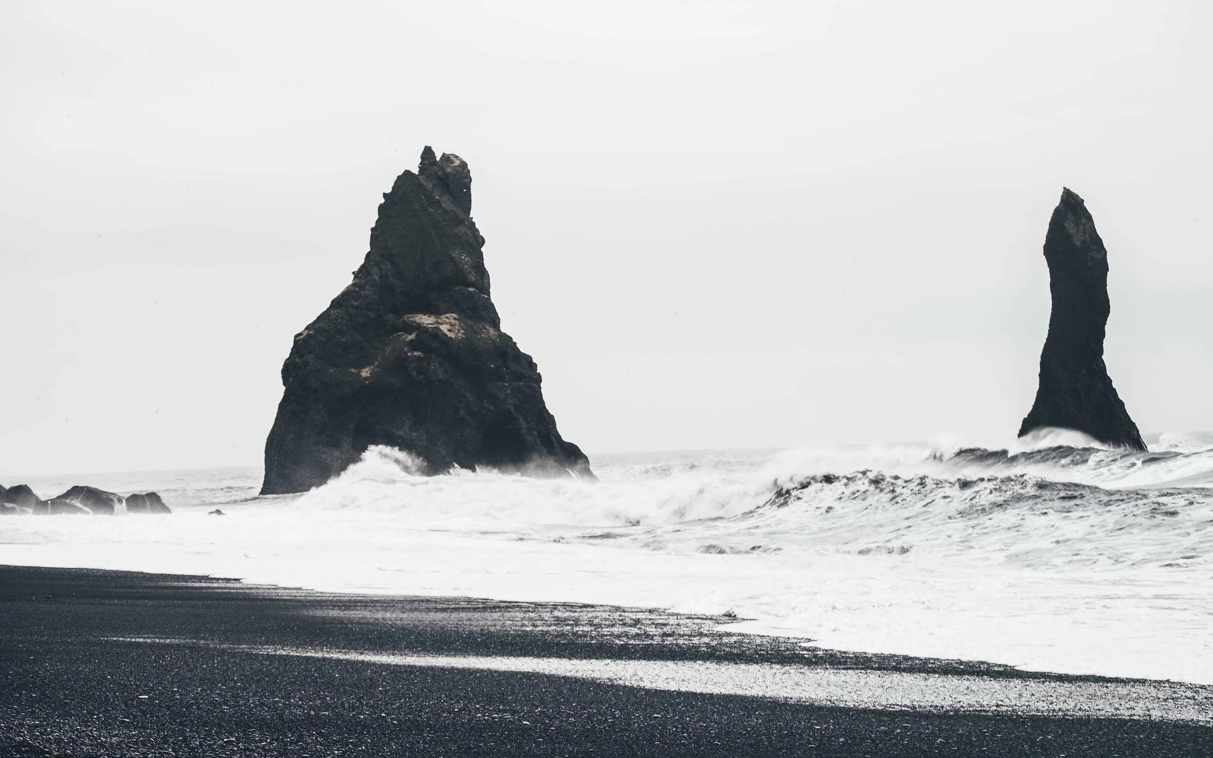Aiguilles de roche noire sur une plage de sable sombre