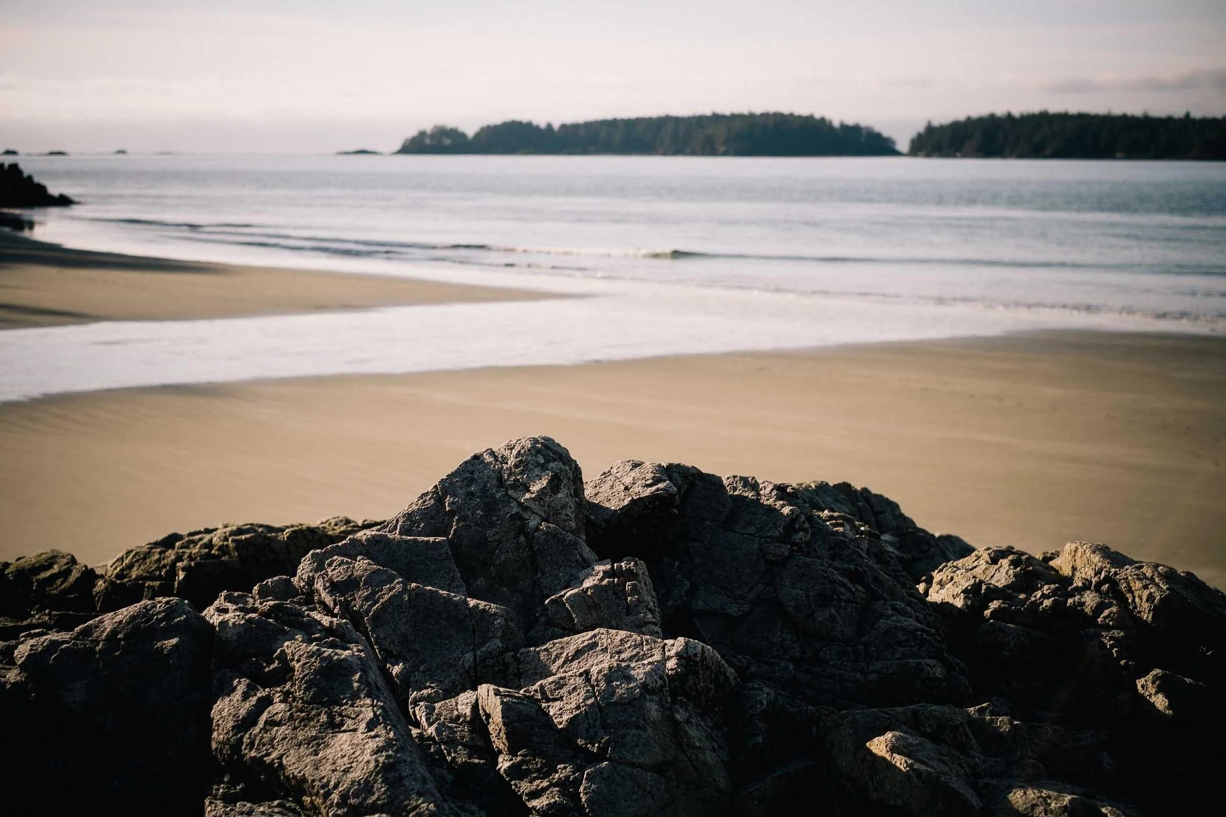 Plage au petit matin, rochers sombres au premier plan