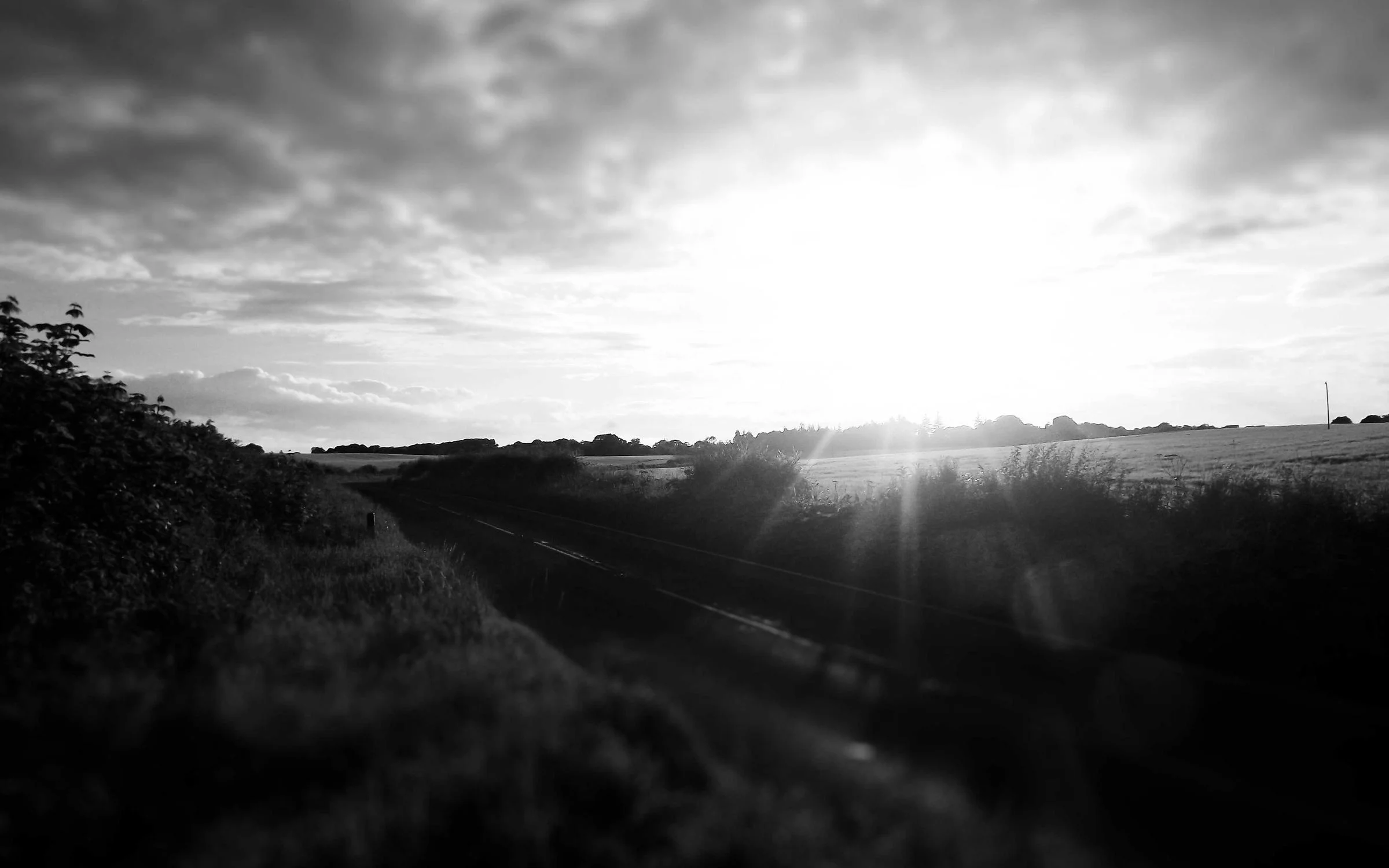 Soleil voilé au-dessus des collines, en noir et blanc