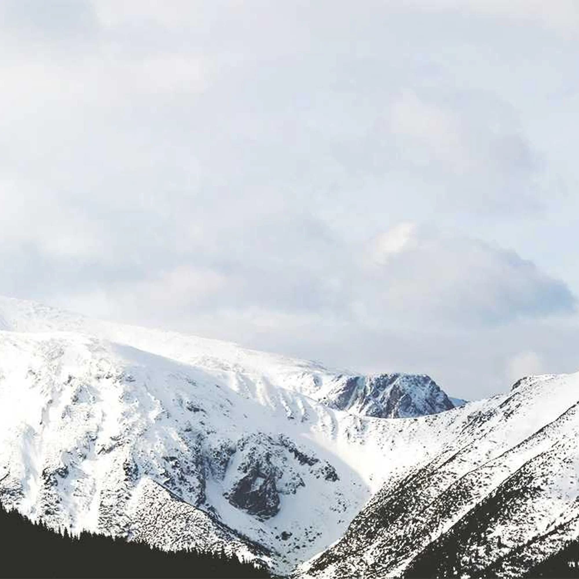 Chaîne de sommets enneigés sous un ciel blanc